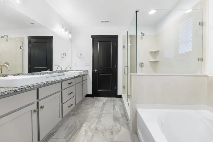 Bathroom featuring a double vanity with granite countertops, vessel sinks, and gold-finish fixtures