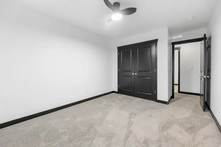 Room with light-toned carpet flooring, white walls, and dark trim