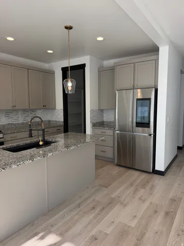 Kitchen featuring wood-finish flooring, recessed lighting, and a kitchen island with a granite countertop and an undermount sink