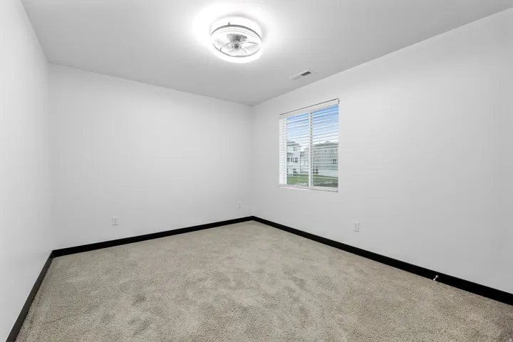Room with a modern flush-mount ceiling light, white walls, and dark baseboards