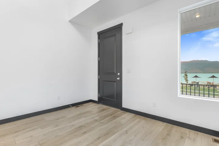 Room with light wood-finish flooring, white walls, and dark trim