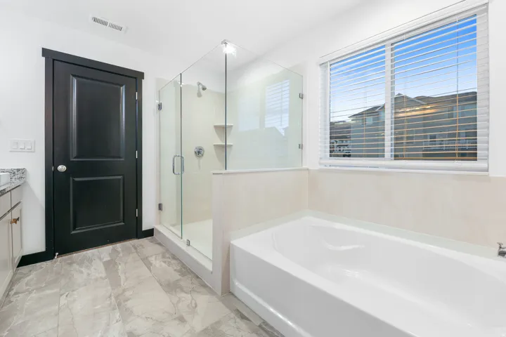 Bathroom featuring a built-in soaking tub and a separate glass-enclosed shower with a tiled surround