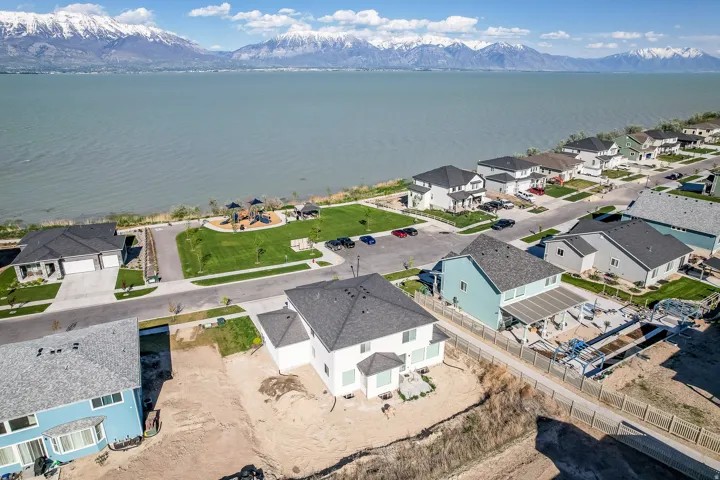 Aerial overview showcasing a residential community situated along a expansive body of water, with snow-capped mountains in the background