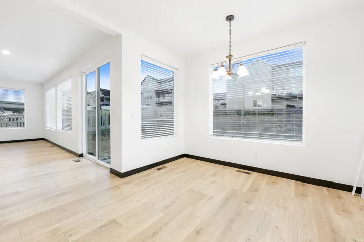 Spacious interior featuring light wood-finish flooring, white walls, and dark baseboards