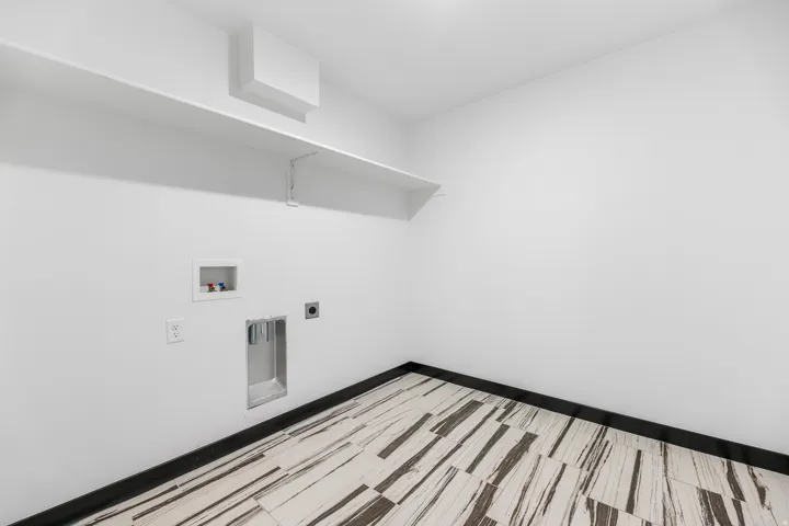 Dedicated laundry space featuring white walls and a white built-in shelf