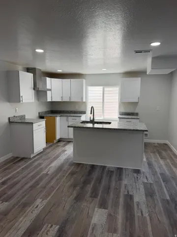 Contemporary kitchen featuring white cabinetry, stone-finish countertops, and wood-finish flooring