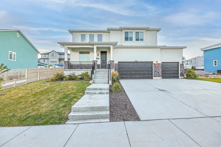Contemporary two-story residence featuring a covered front porch, a two-car garage, a concrete driveway, and a front lawn with mature landscaping