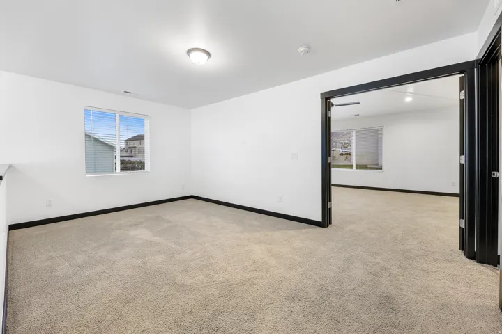 Carpeted room with a flush-mount ceiling light and a single window with horizontal blinds