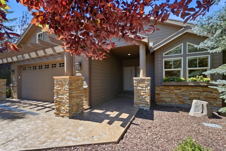Stucco siding with stone accents, an attached two-car garage, and a stamped concrete driveway