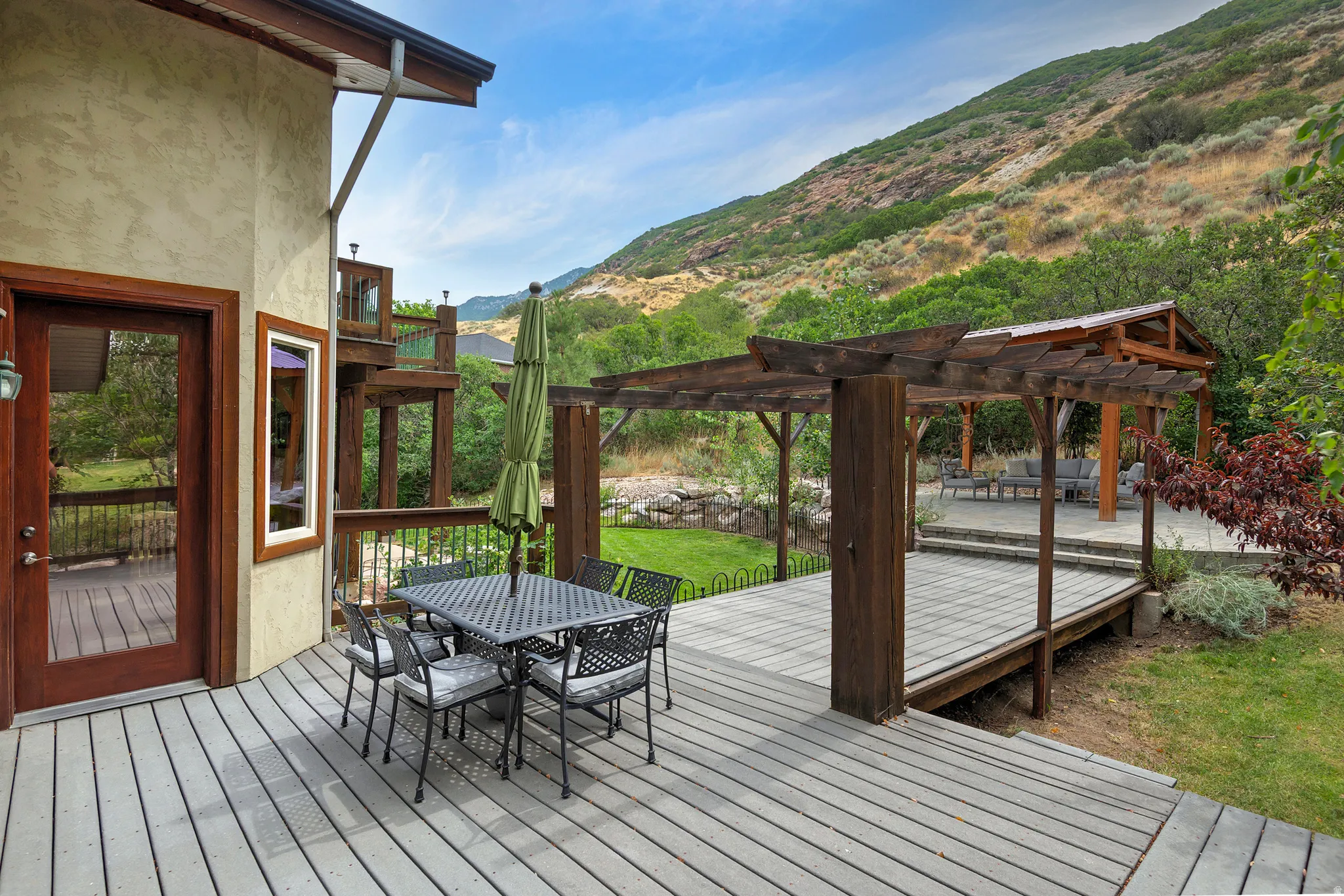 Expansive outdoor decking featuring a pergola, built-in gazebo, and mountain backdrop
