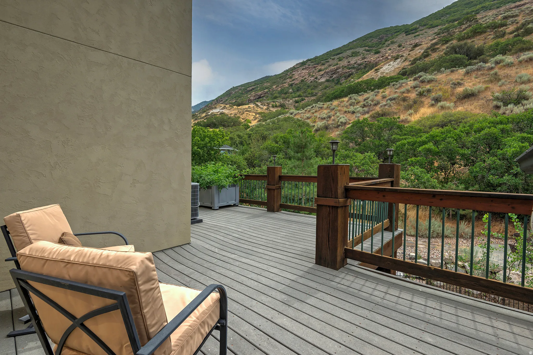Spacious outdoor deck featuring composite decking, a sturdy wood railing with metal balusters, and integrated post-top lighting