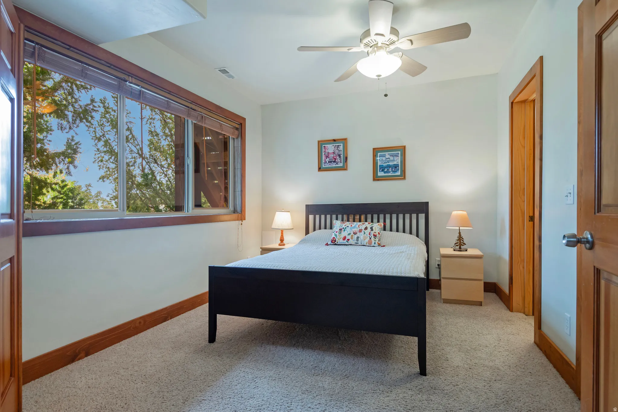 Light-filled room featuring a broad window with wood-finish trim, neutral wall paint, and a textured carpet