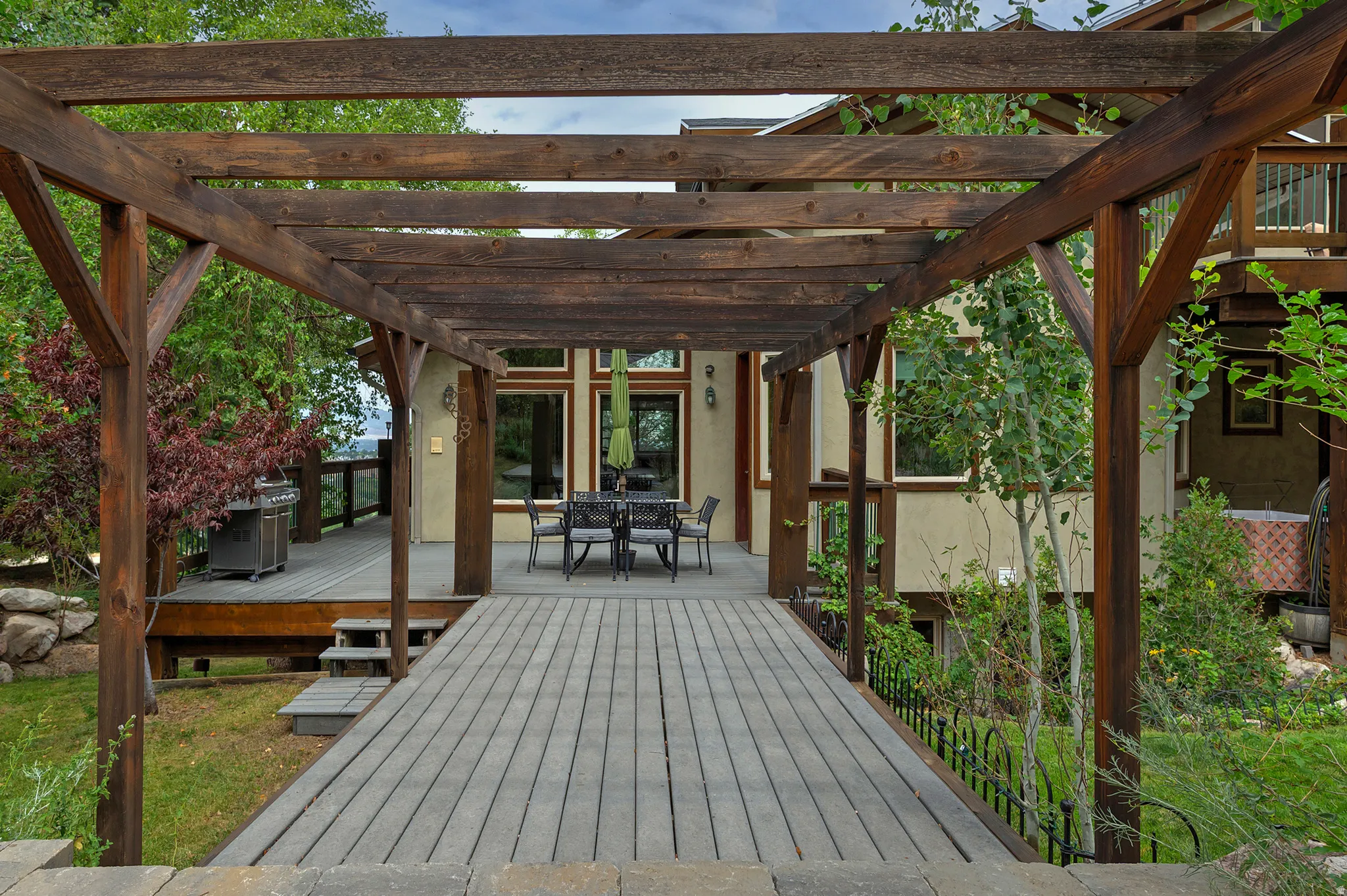 Outdoor entertaining space featuring a pergola-covered walkway with paver decking