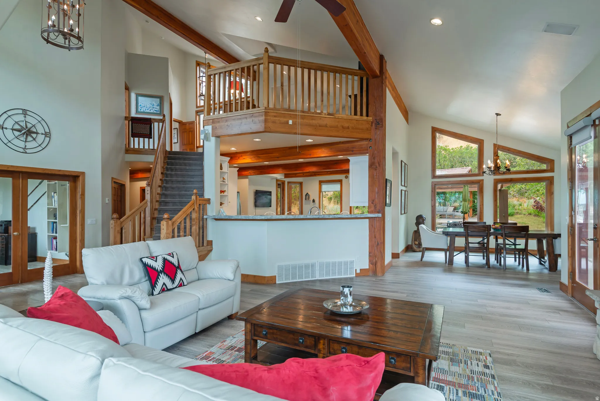 Vaulted ceilings featuring exposed wood beams, a prominent staircase with wood railings, and a second-story interior balcony