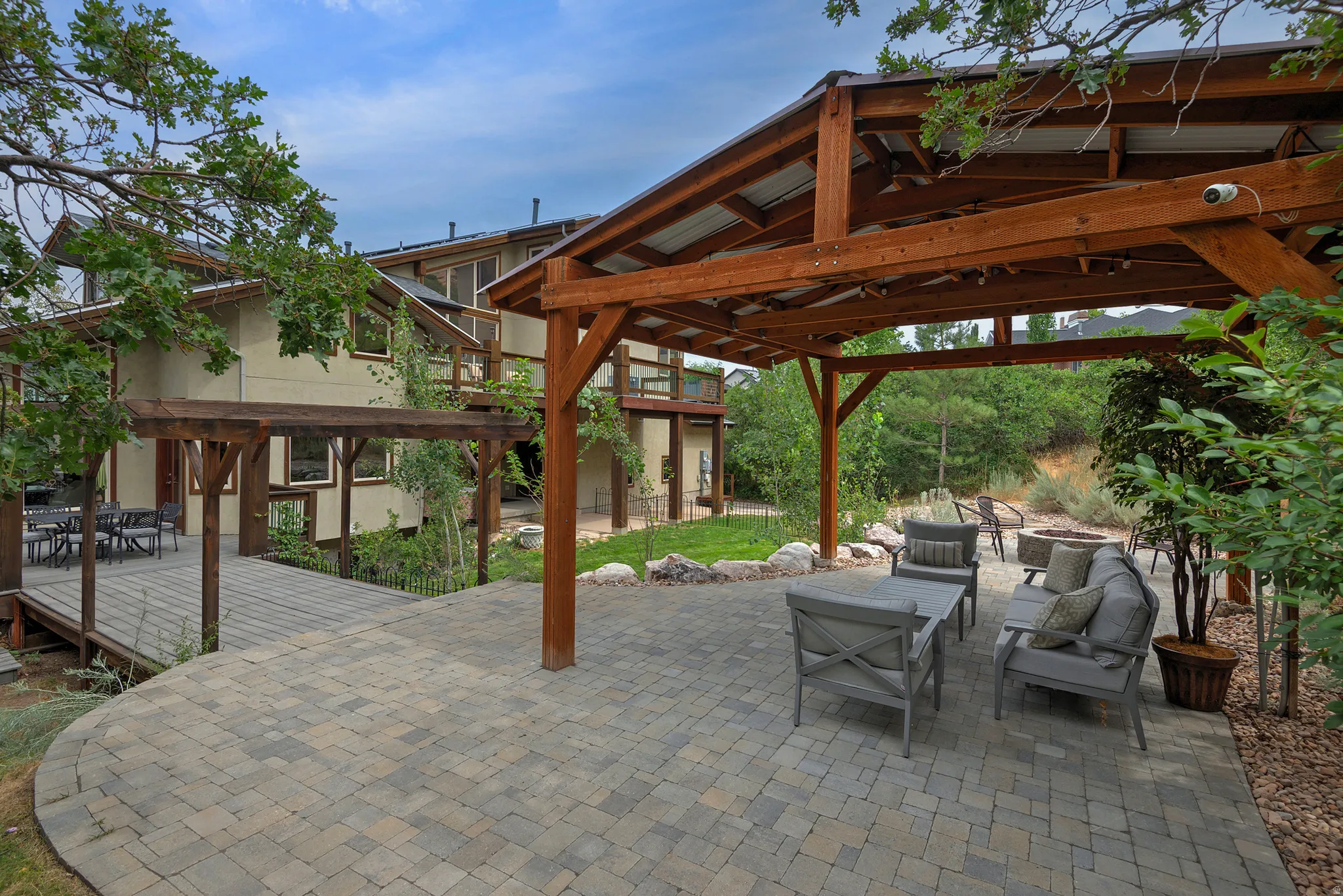 Expansive outdoor patio featuring a paver stone surface and a substantial wood pergola with a metal roof