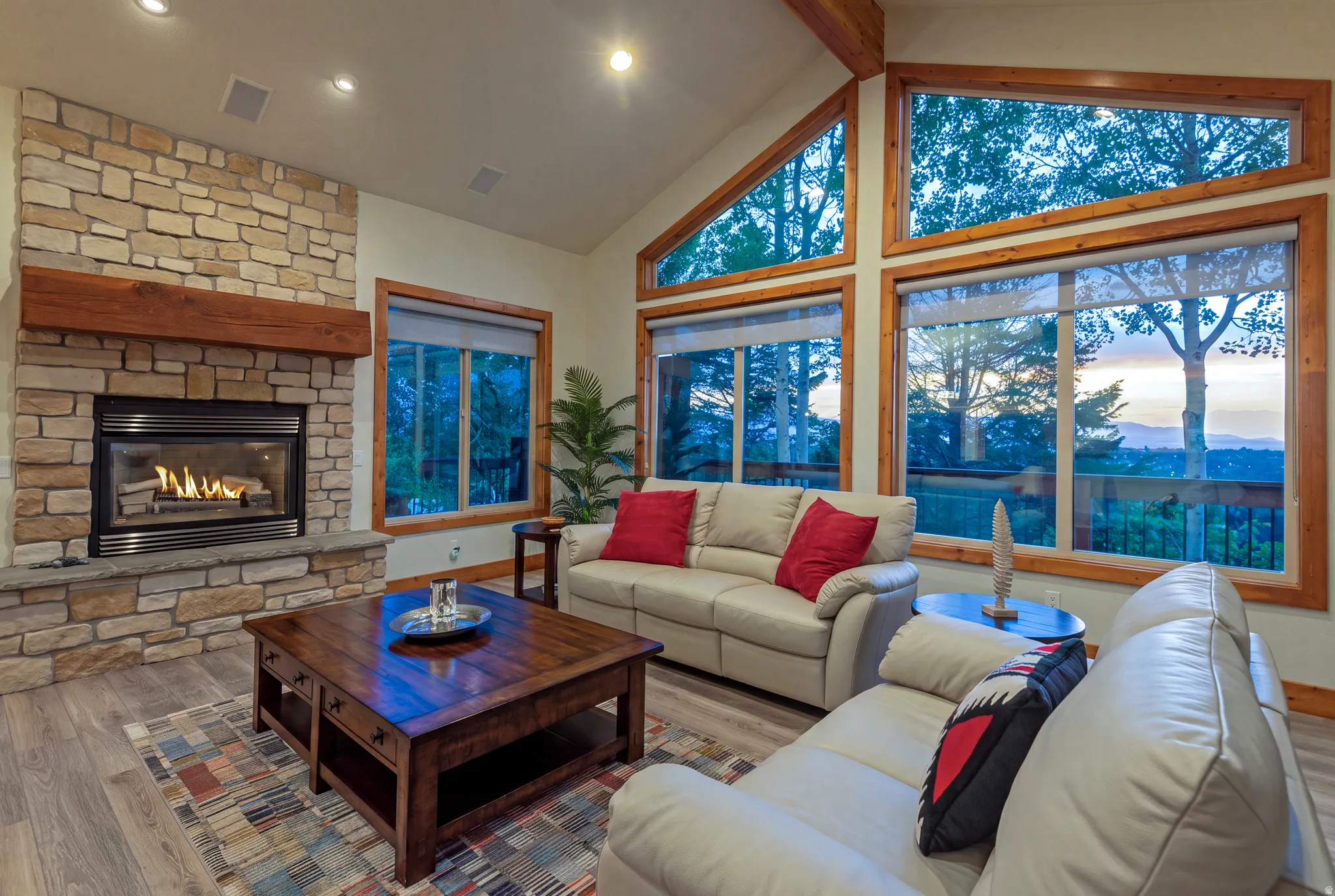Vaulted living space featuring a stone-clad fireplace with a wood mantel and recessed lighting
