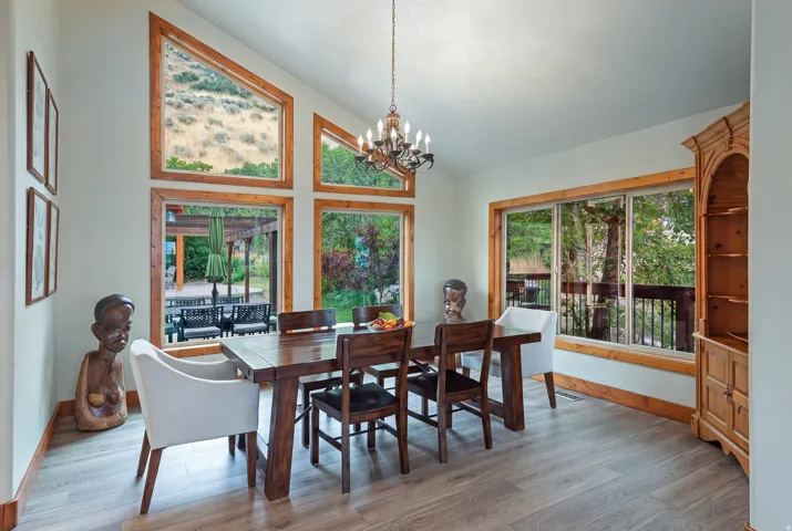 Vaulted ceiling dining area featuring expansive wood-trimmed windows, a multi-paneled window wall, and wood-finish flooring