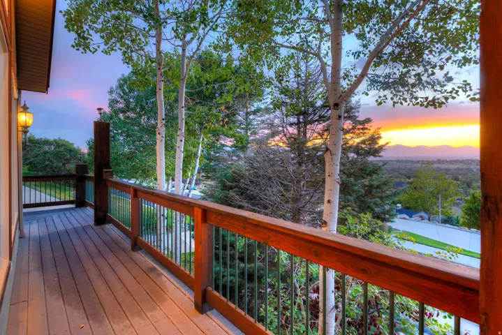 Spacious outdoor deck featuring wood-finish flooring, a sturdy wood railing with metal balusters, and an attached exterior wall lantern