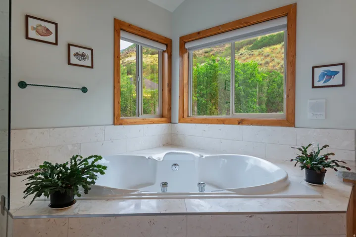 Built-in soaking tub featuring polished chrome fixtures, surrounded by a light-toned tile deck and wall