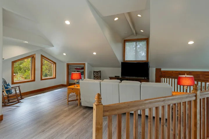 Spacious loft area featuring recessed lighting, light wood-finish flooring, and multiple angled windows with wood trim