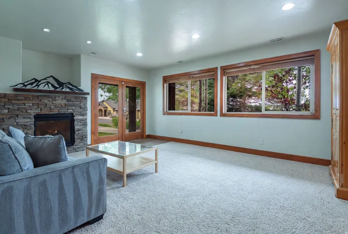 Spacious room featuring a stone-clad fireplace with a wood mantel, recessed lighting, and wood-framed windows