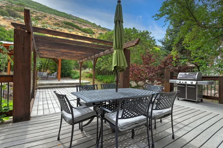Expansive outdoor deck featuring wood-finish composite decking, a wood pergola, and a built-in stainless steel grill