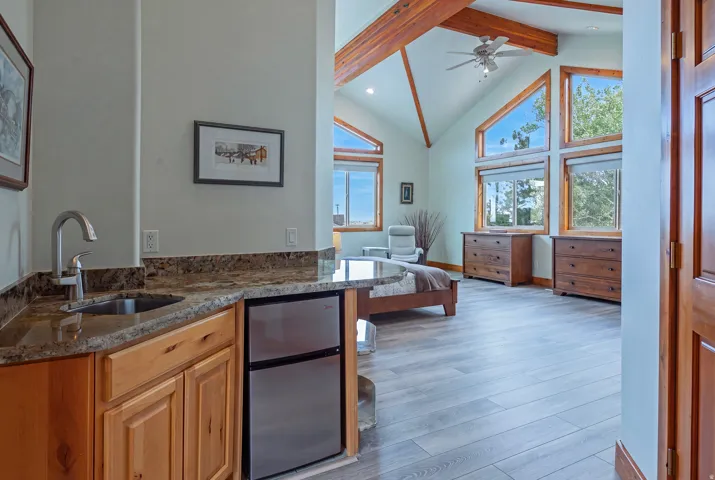 Wet bar with granite-style countertop, stainless steel sink, and compact refrigerator