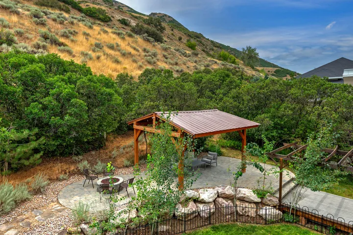 Outdoor living space featuring a wood pergola with a metal roof, a circular paver patio, and a separate stone patio