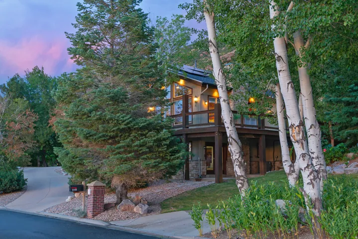 Elevated residence featuring a multi-level deck, expansive windows, and a stone-clad foundation