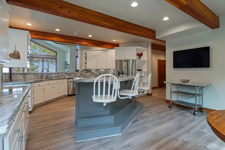 Kitchen with an island featuring a raised bar, white cabinetry, and stone countertops