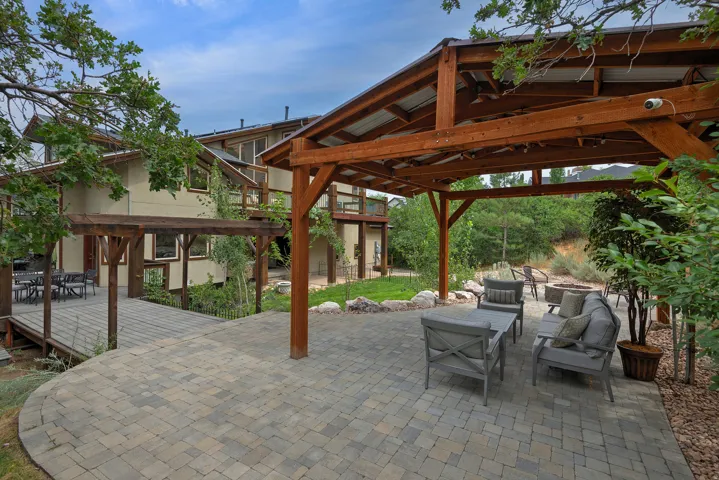 Expansive outdoor patio featuring a paver stone surface and a substantial wood pergola with a metal roof