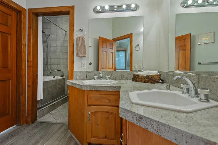 Bathroom featuring dual undermount sinks, stone countertops, and wood-finish cabinetry