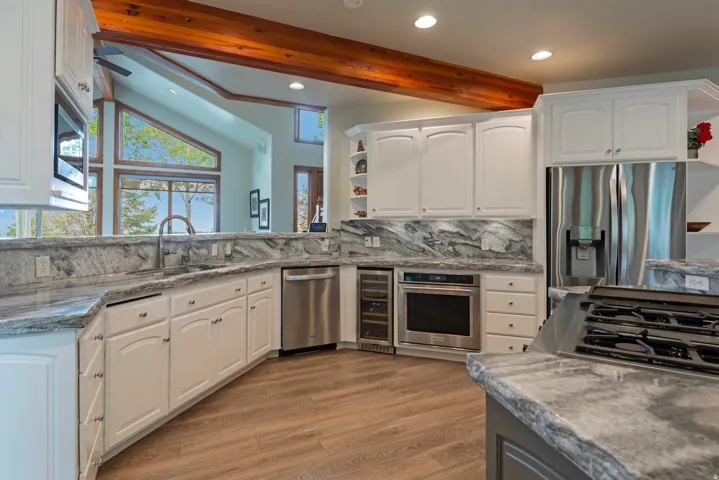 Modern kitchen featuring wood-finish flooring, white cabinetry, and gray stone countertops with matching backsplash