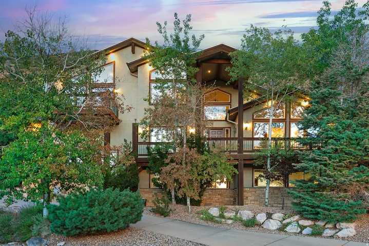 Contemporary stucco exterior featuring expansive fenestration, multiple balconies, a covered entryway, and stone accents