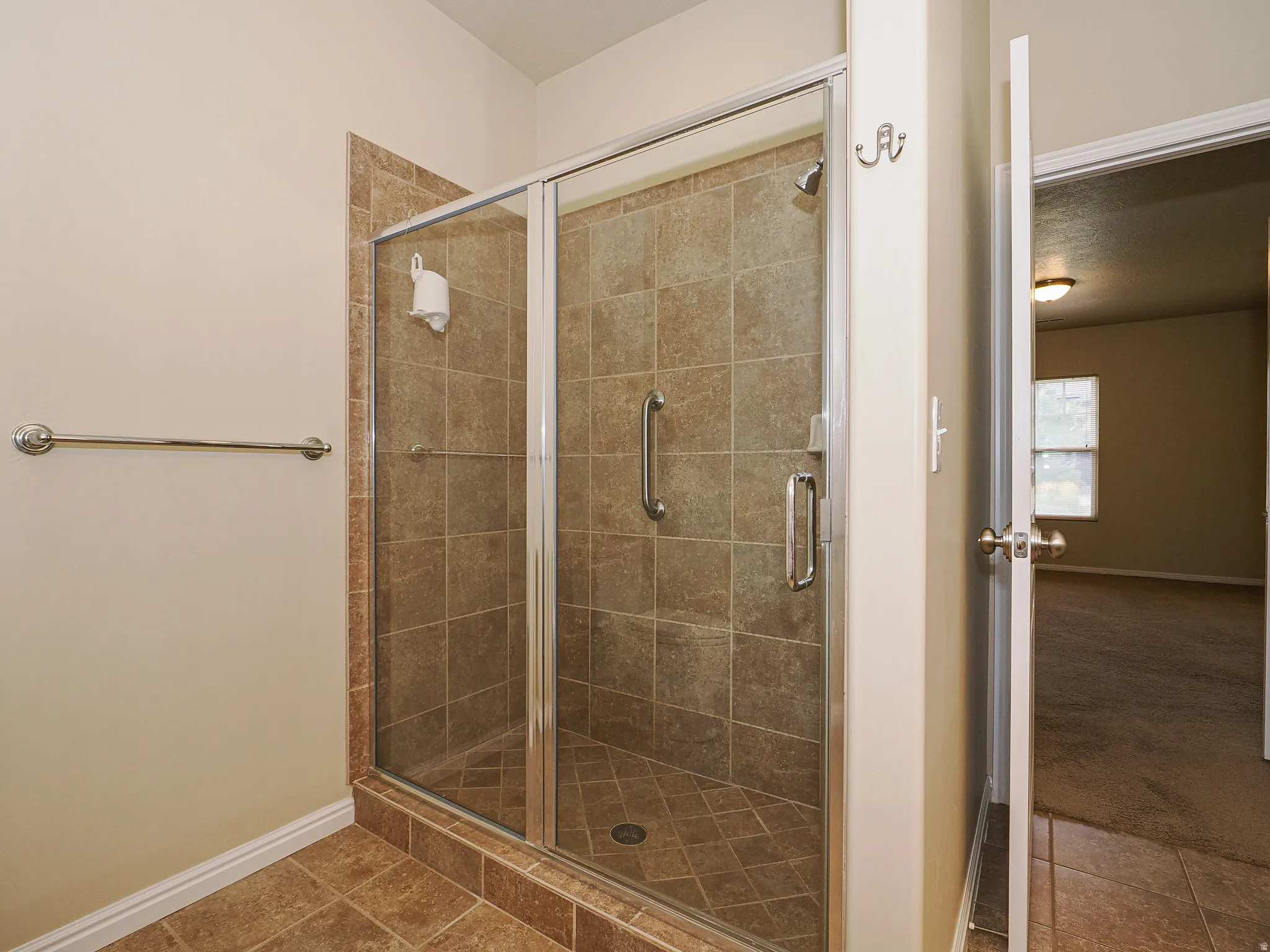 Tile-surround shower with glass enclosure, chrome fixtures, and built-in grab bar