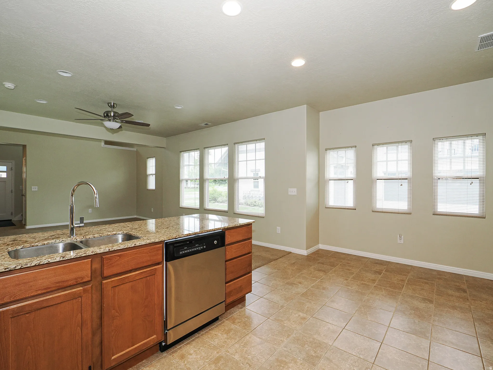 Kitchen island with granite countertops, stainless steel double basin sink, and integrated dishwasher