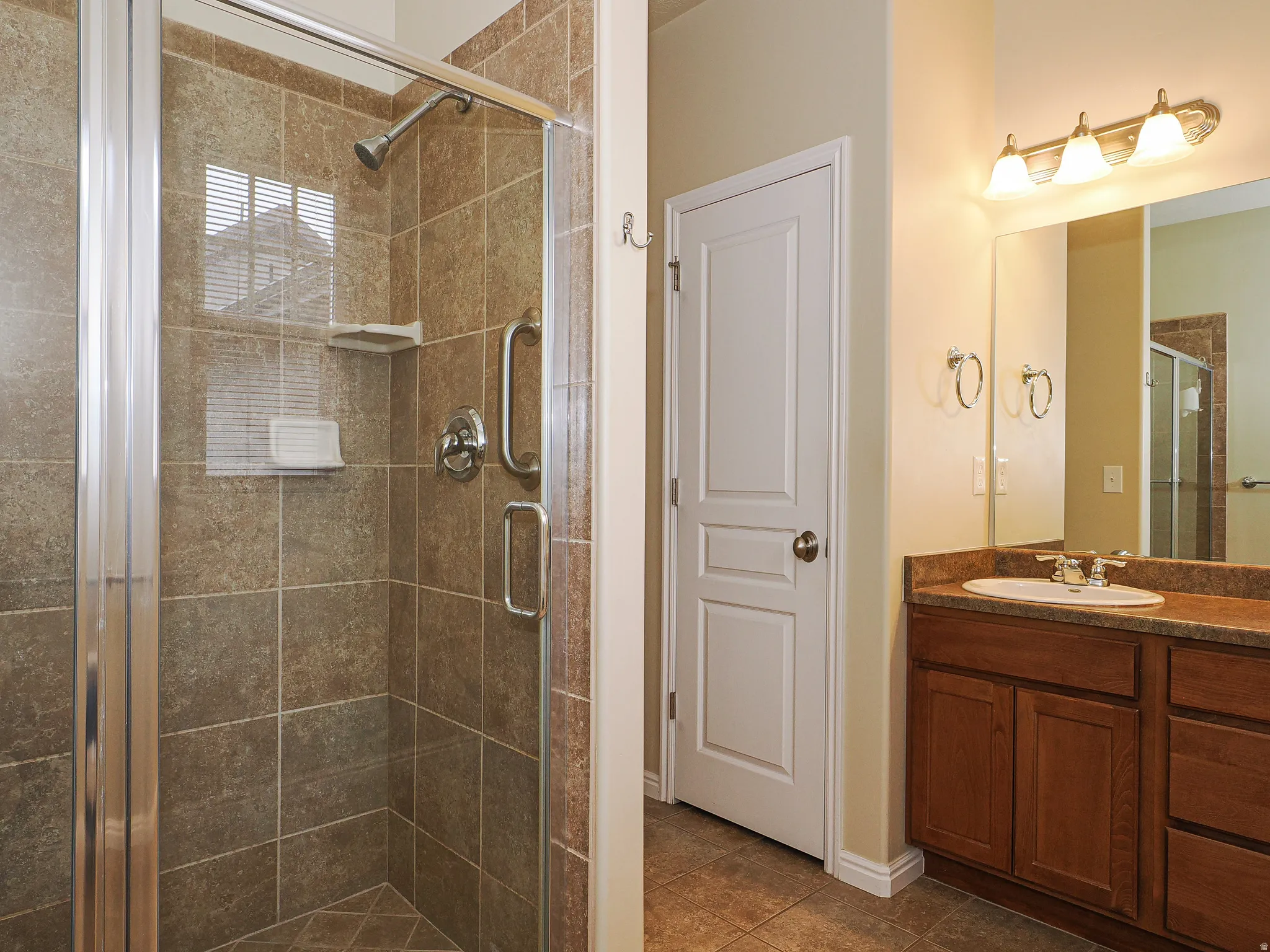 Bathroom featuring a walk-in shower with tile surround, glass enclosure, and grab bar