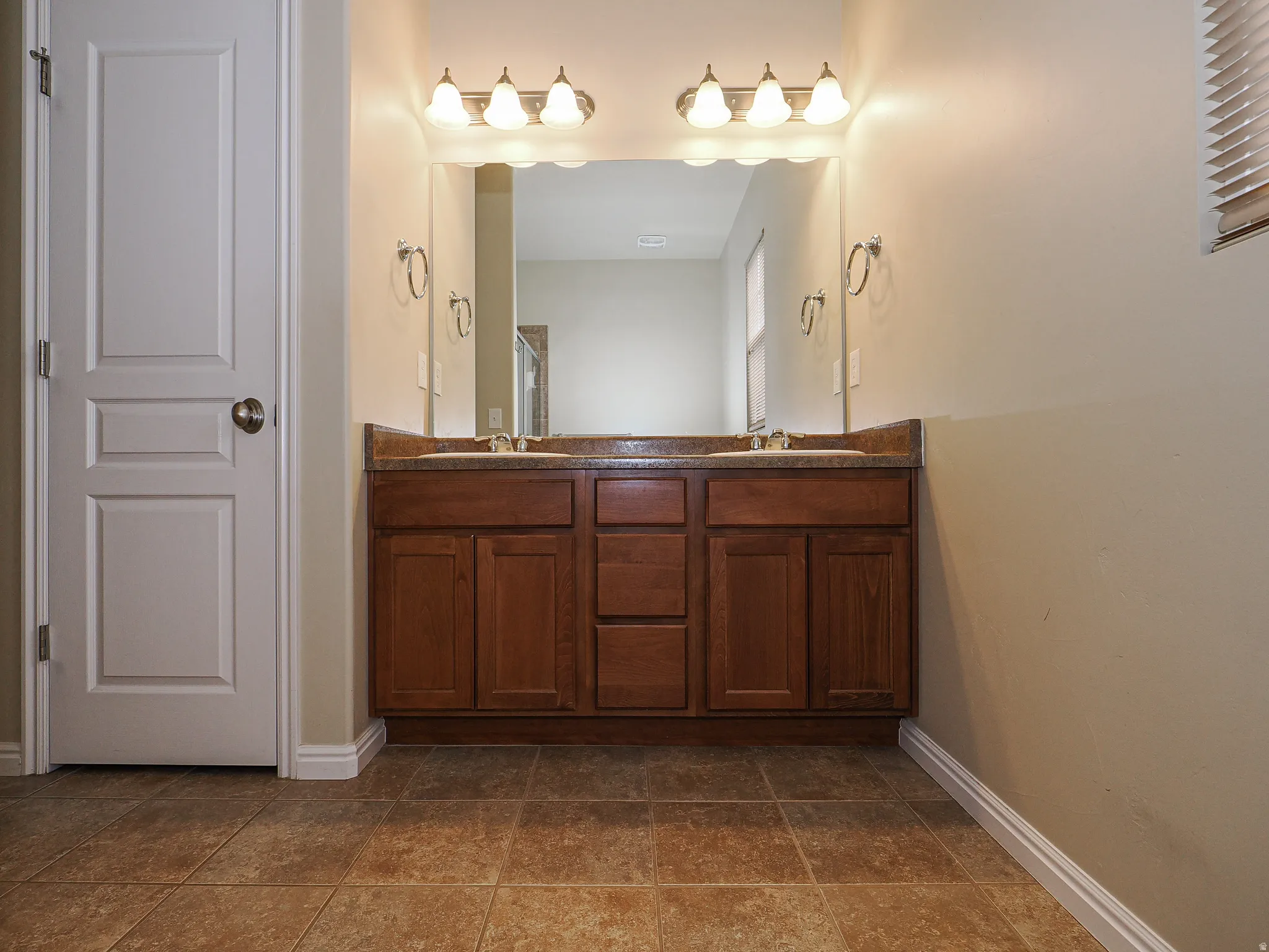Dual vanity with wood-finish cabinetry, integrated sinks, and a stone-look countertop