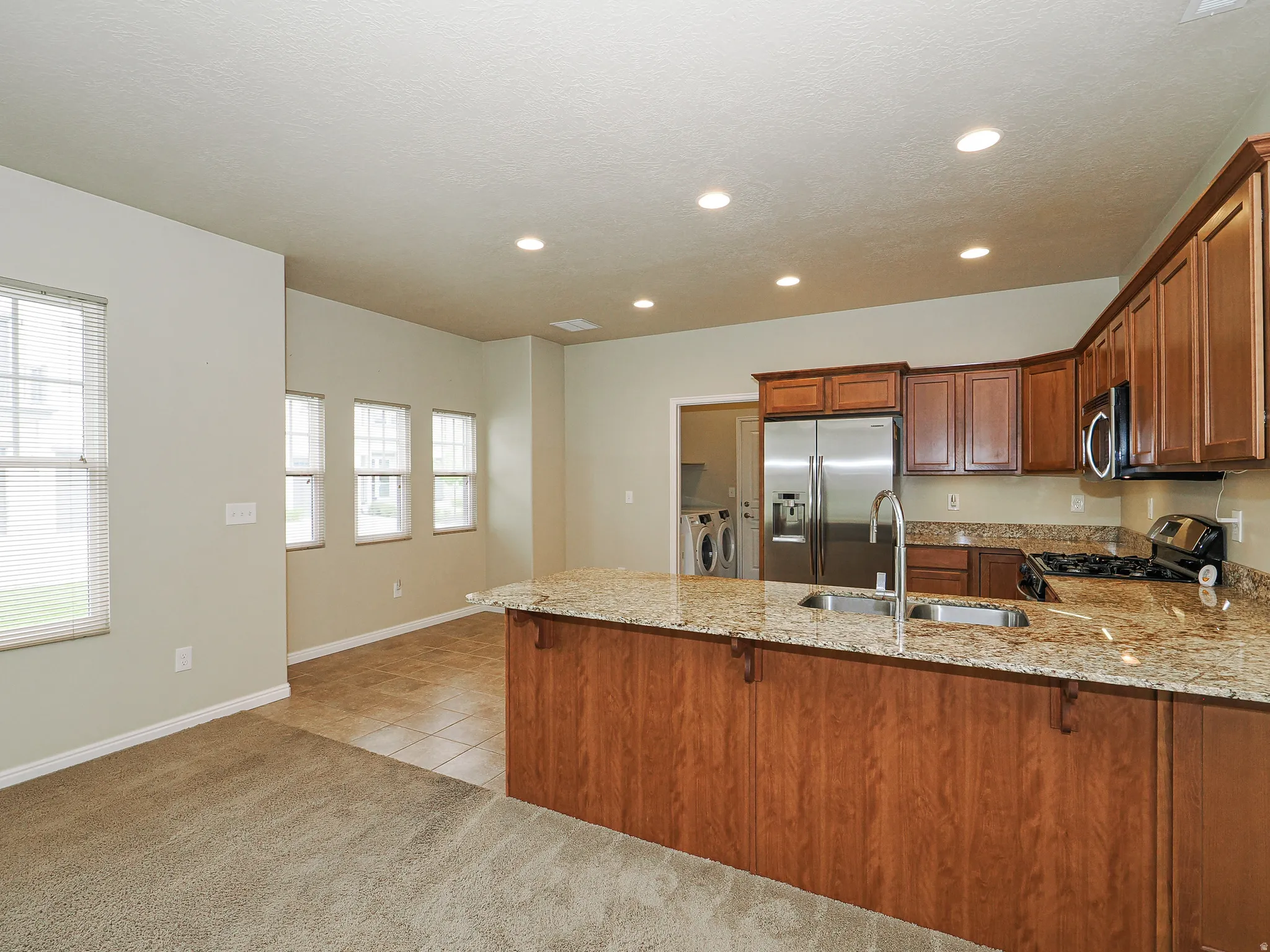 Kitchen featuring granite countertops, wood cabinetry, stainless steel appliances, and recessed lighting