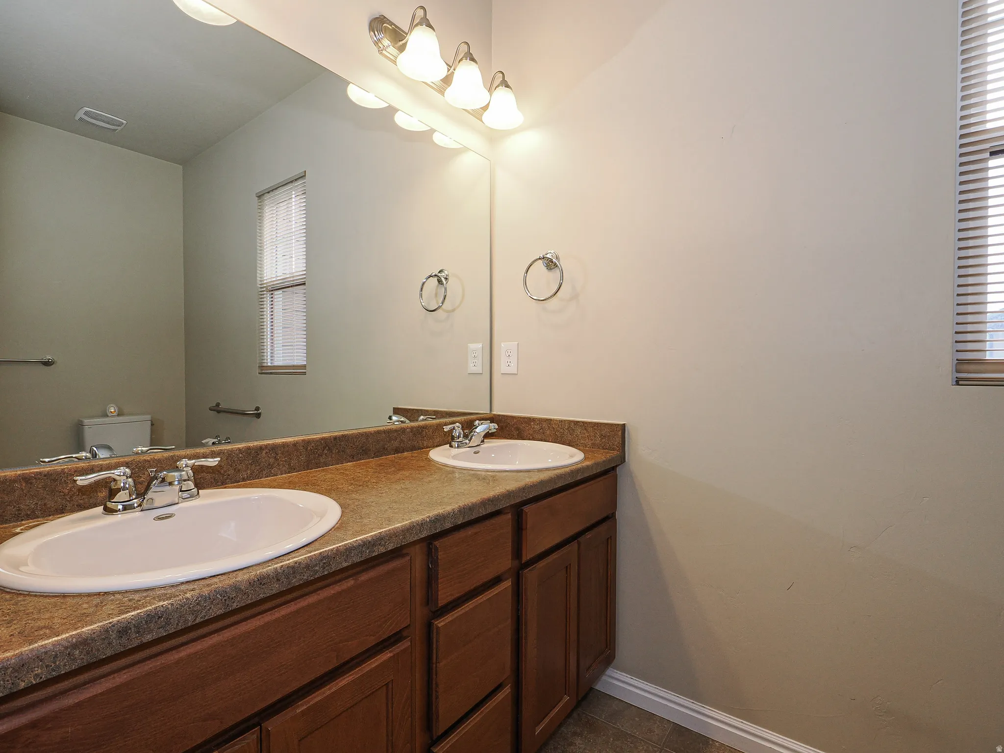 Dual vanity with integrated sinks, wood-finish cabinetry, and a broad countertop