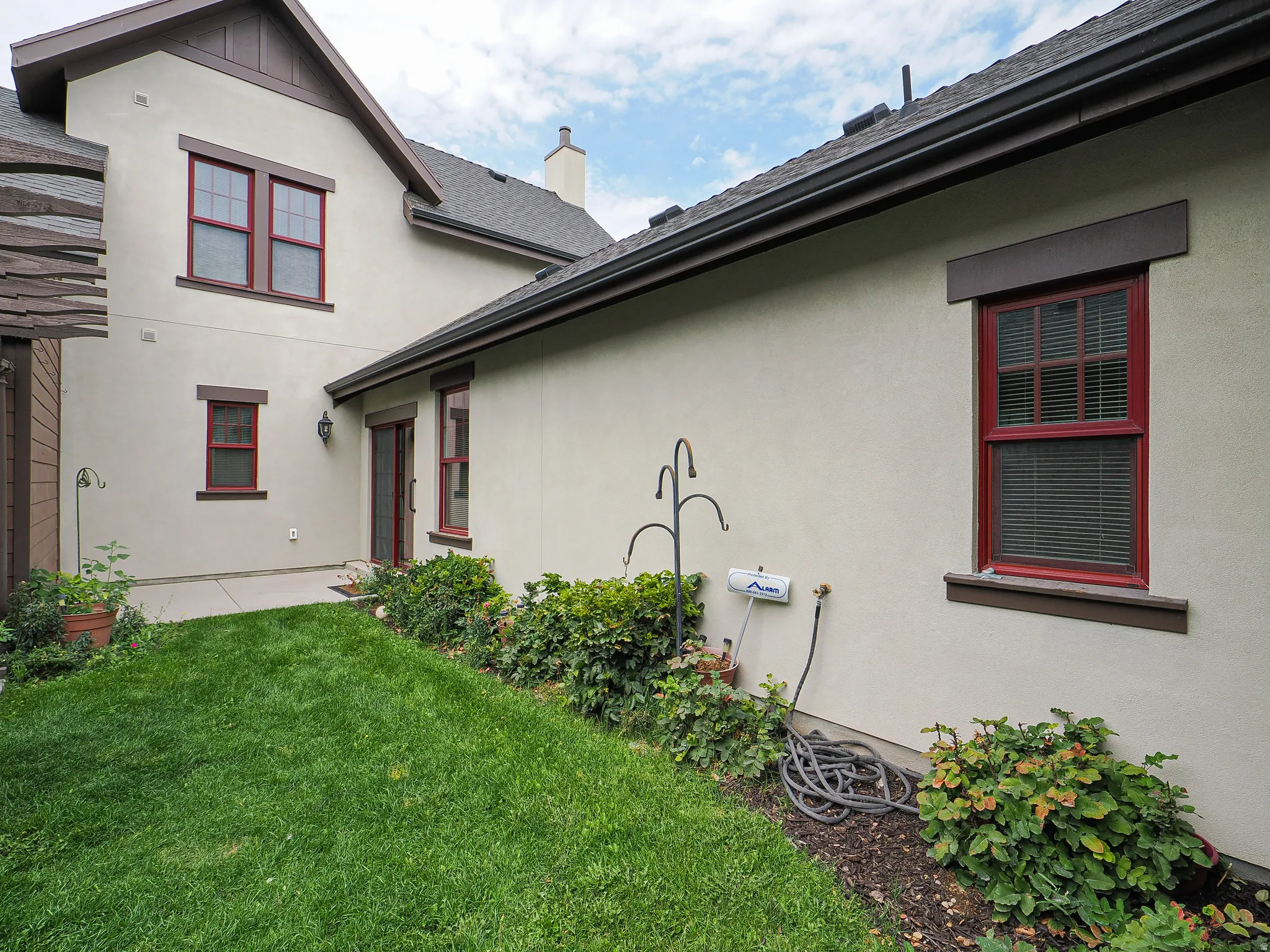 Stucco exterior with brown trim accents and red-framed windows