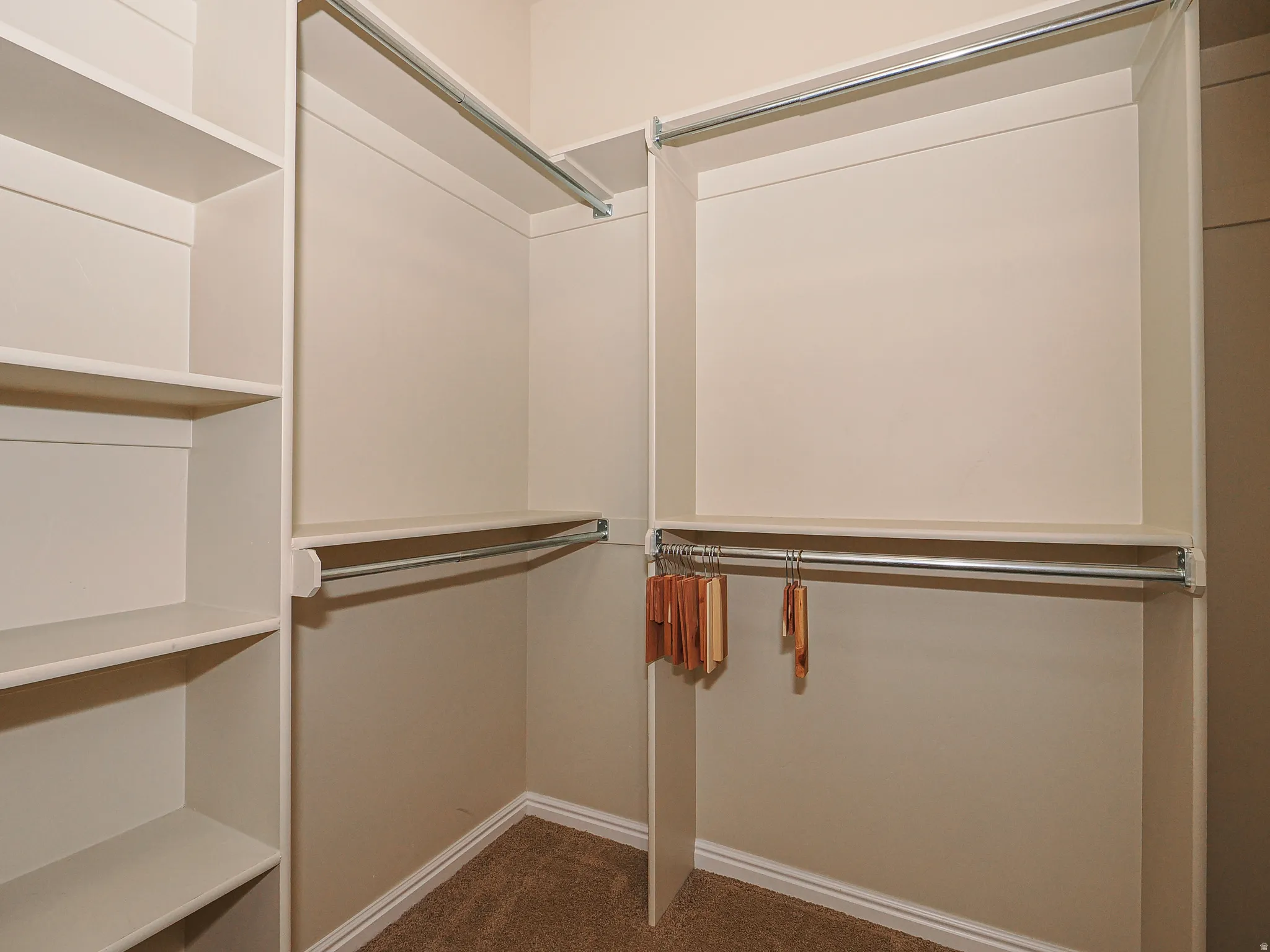 Custom closet system featuring built-in shelving, multiple hanging rods, and light-toned walls