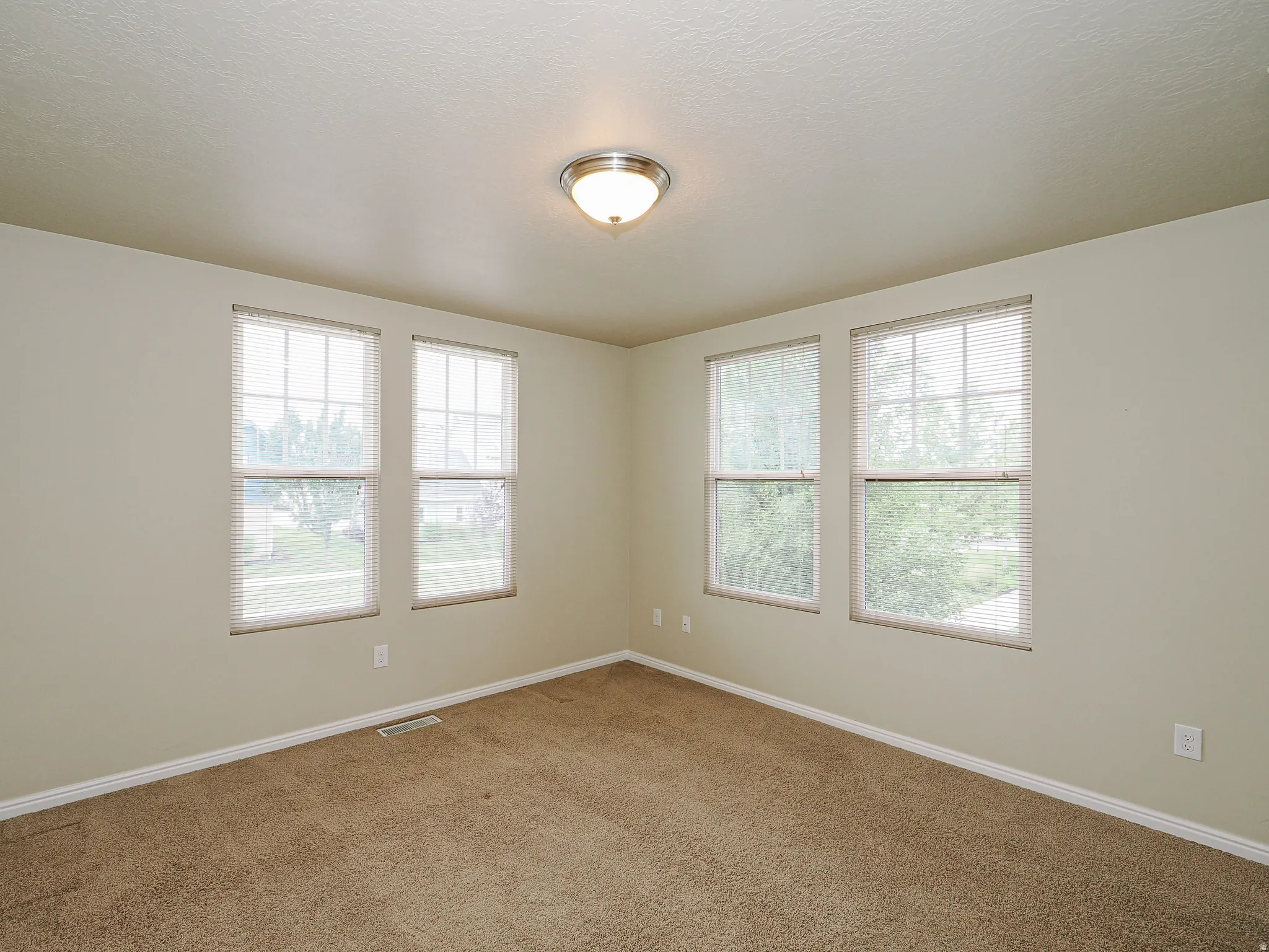 Wall-to-wall carpeting with multiple windows featuring horizontal blinds
