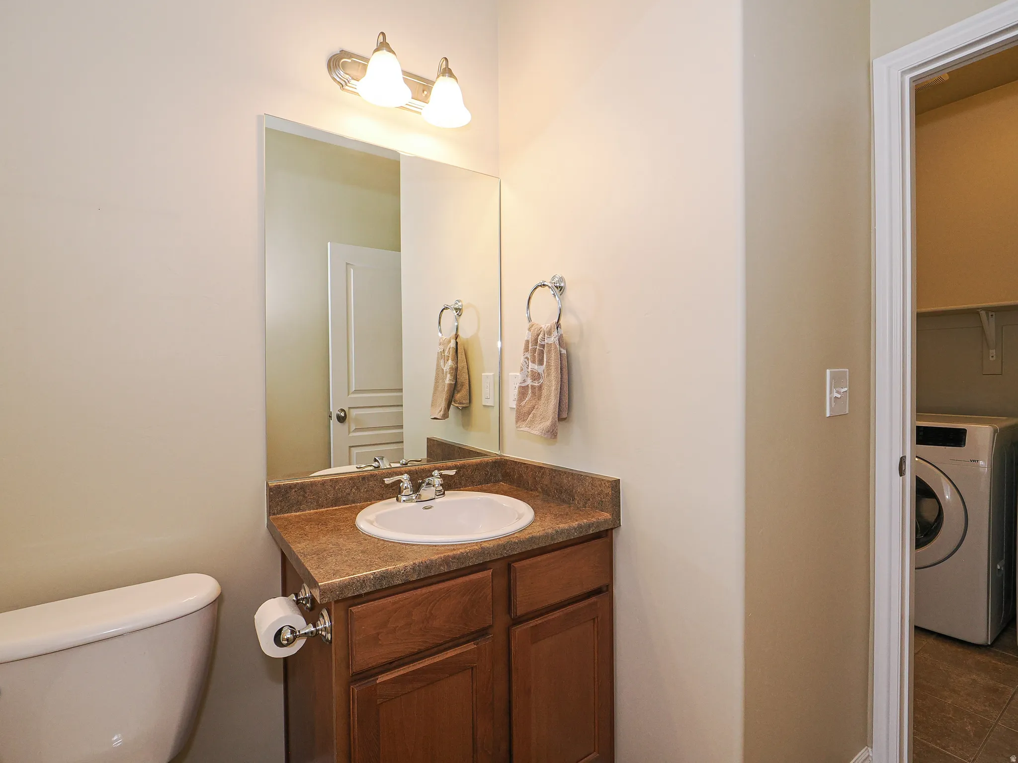 Bathroom vanity with a white basin sink, chrome faucet, and wood-finish cabinetry