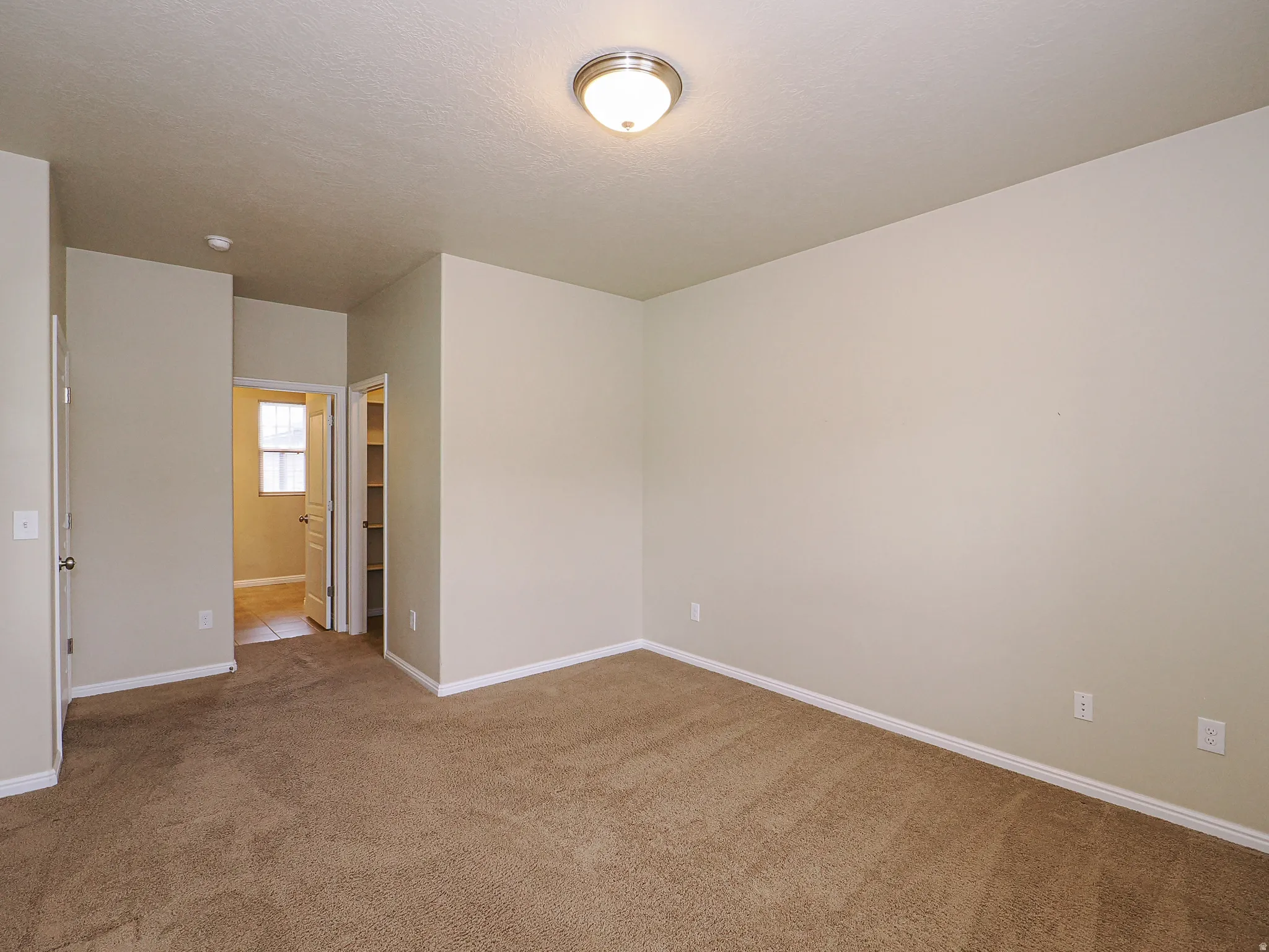 Neutral-toned room with plush carpeting, offering a warm and inviting atmosphere