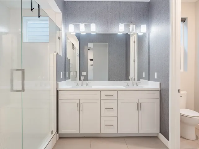 Double vanity featuring shaker-style cabinetry, white countertops, and brushed nickel fixtures
