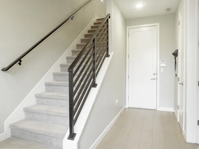 Modern staircase featuring metal horizontal bar railing and carpeting