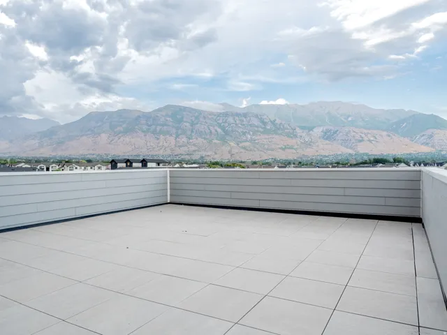 Expansive rooftop deck featuring light-toned tile flooring and a neutral-colored privacy wall