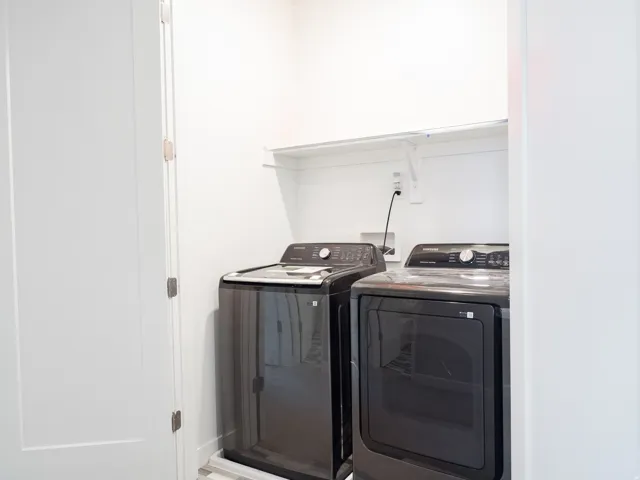 Dedicated laundry area featuring a white wall shelf, utility hookups, and light-toned flooring