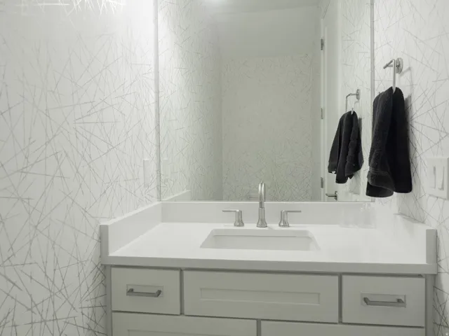 Modern vanity featuring white cabinetry with brushed nickel hardware, a white countertop, and an undermount sink with a chrome faucet